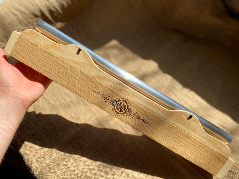 May include: A wooden box with a silver metal bar inside. The box has a geometric design burned into the wood.