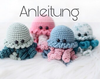 May include: Four crocheted jellyfish amigurumi toys in different colors: teal, pink, light blue, and white. The word "Anleitung" is written in black text at the top of the image.