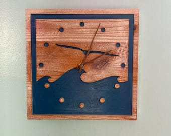 May include: A wooden clock with a blue background and a wave design. The clock hands are brown and the clock face has a seagull design.