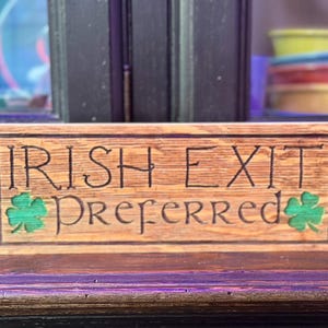 K&ouml;nnte beinhalten: Holzschild mit den Worten "IRISH EXIT Preferred" in das Holz geschnitzt. Das Schild hat gr&uuml;ne Kleebl&auml;tter auf beiden Seiten des Wortes "Preferred". Das Schild ist aus hellbraunem Holz.