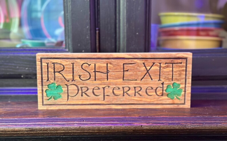 K&ouml;nnte beinhalten: Holzschild mit den Worten "IRISH EXIT Preferred" in das Holz geschnitzt. Das Schild hat gr&uuml;ne Kleebl&auml;tter auf beiden Seiten des Wortes "Preferred". Das Schild ist aus hellbraunem Holz.