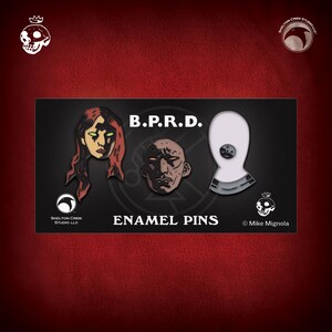 Puede incluir: Tres pines de esmalte con personajes de la serie de cómics B.P.R.D. Los pines son negros y blancos con acentos rojos. Los personajes son una mujer con cabello rojo, un hombre calvo y una figura con una capa blanca con capucha. El texto "B.P.R.D." y "ENAMEL PINS" también es visible en la imagen. © Mike Mignola.