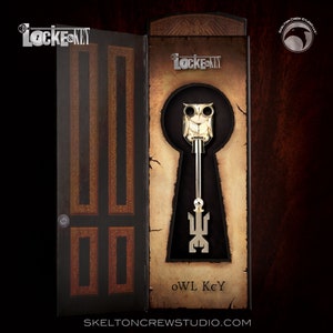 Pode incluir: Uma chave de coruja dourada com um design de buraco de fechadura, exibida em uma caixa com as palavras "Locke & Key" e "OWL Key".