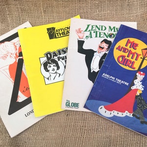 May include: Four playbills for different musicals. The playbills are all different colours and have different designs. The playbills are all for musicals that were performed in London. The playbills are all for musicals that were performed in the 1980s.