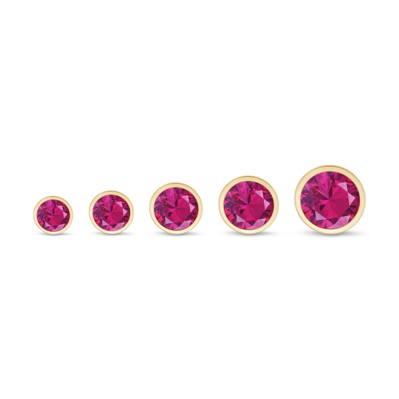 May include: Five gold stud earrings, each featuring a round, fuchsia gemstone. The earrings are displayed in a row, varying in size. The gemstones are set in a simple bezel setting, with a bright, polished finish.