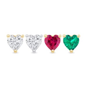 May include: Four heart-shaped stud earrings. The earrings feature clear, red, and green gemstones. The studs have gold and silver settings. The gemstones are faceted and sparkle.