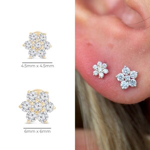 May include: Gold-toned flower stud earrings with clear, sparkling stones. The earrings are available in two sizes: 4.5mm x 4.5mm and 6mm x 6mm. One earring is shown on an ear.