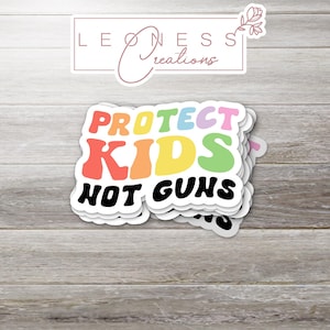 May include: A stack of colorful stickers with the text "PROTECT KIDS NOT GUNS" in a rainbow font.