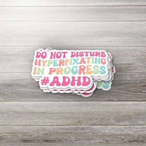 May include: A stack of colorful stickers with the text "Do Not Disturb Hyperfixating In Progress #ADHD".
