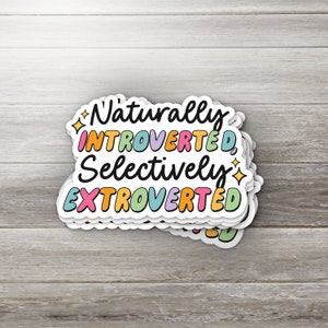 May include: A sticker with the text "Naturally Introverted, Selectively Extroverted" in colorful, outlined letters. The sticker is layered and has a white background.