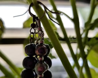 May include: A pair of dangle earrings with a silver hook and multiple dark purple beads.