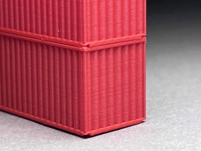May include: Close-up of a red corrugated cardboard box. The box is made of thick cardboard and has a textured surface.