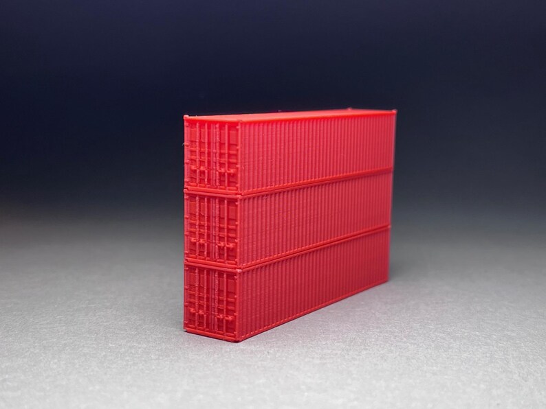 May include: Three red shipping containers stacked on top of each other. The containers are made of metal and have a corrugated surface.