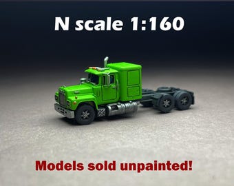 Może przedstawiać: Zielony model ciężarówki w skali N 1:160. Miniaturowa ciężarówka ma szczegółową kabinę i podwozie z czarnymi kołami i srebrnymi akcentami. Tekst "Models sold unpainted!" jest wyświetlany poniżej.