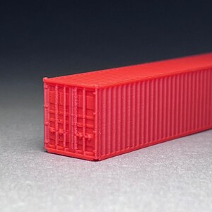 May include: A red shipping container model. The container is made of plastic and has a corrugated texture. The container is about 10 inches long.
