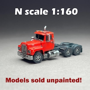 May include: A red N scale 1:160 model truck cab, unpainted, with black wheels and a detailed interior. Models sold unpainted.
