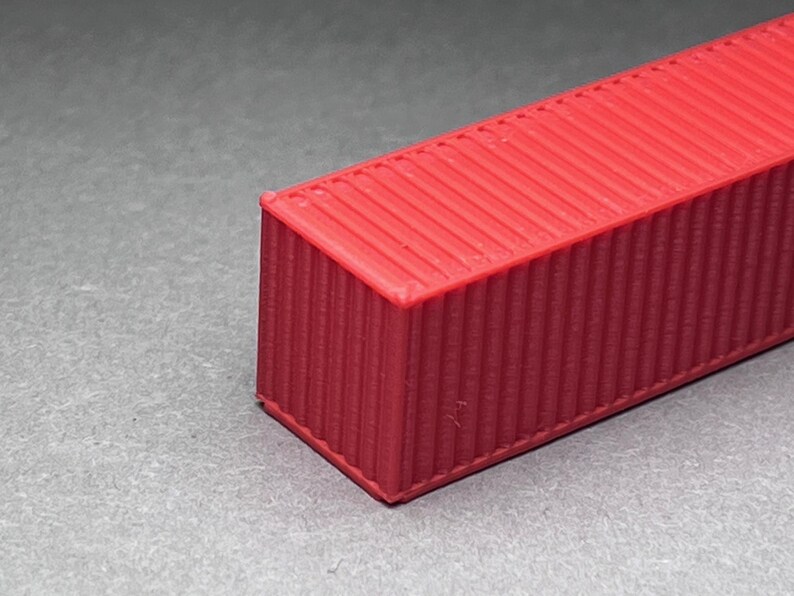 May include: A red shipping container model with a corrugated metal texture.