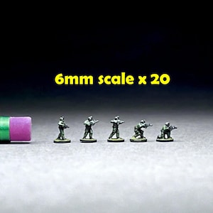 May include: A set of 20 6mm scale plastic figures of soldiers in camouflage uniforms, holding rifles. The figures are standing on a gray surface.