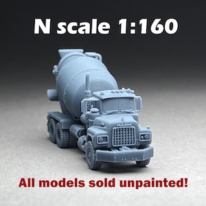 May include: A gray, unpainted N scale (1:160) model of a Mack cement mixer truck. The model features detailed components, including the rotating drum, cab, and wheels. Text on the image reads "All models sold unpainted!"