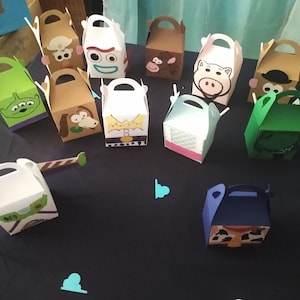 Puede incluir: Una colecci&oacute;n de cajas de regalo coloridas con temas de personajes, inspiradas en una popular pel&iacute;cula animada. Las cajas presentan varios personajes, con asas para facilitar el transporte. Las cajas est&aacute;n dispuestas sobre una superficie azul oscuro.