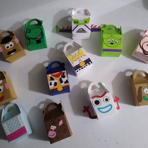 Puede incluir: Una colecci&oacute;n de cajas de regalo coloridas y hechas a mano con personajes de la pel&iacute;cula animada Toy Story. Las cajas son de varios colores y formas, con asas y caras de personajes como Sr. Cara de Papa, Rex y Buzz Lightyear.