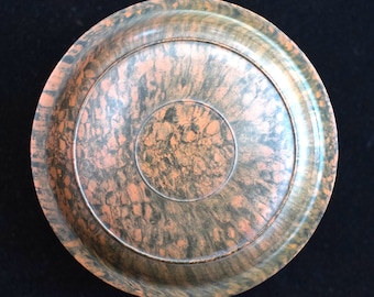 Peut inclure: Un plat rond en plastique marbré noir et orange avec un bord surélevé.