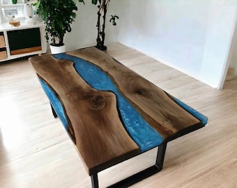 May include: A wooden table with a blue epoxy resin river running through the center. The table has a black metal base.