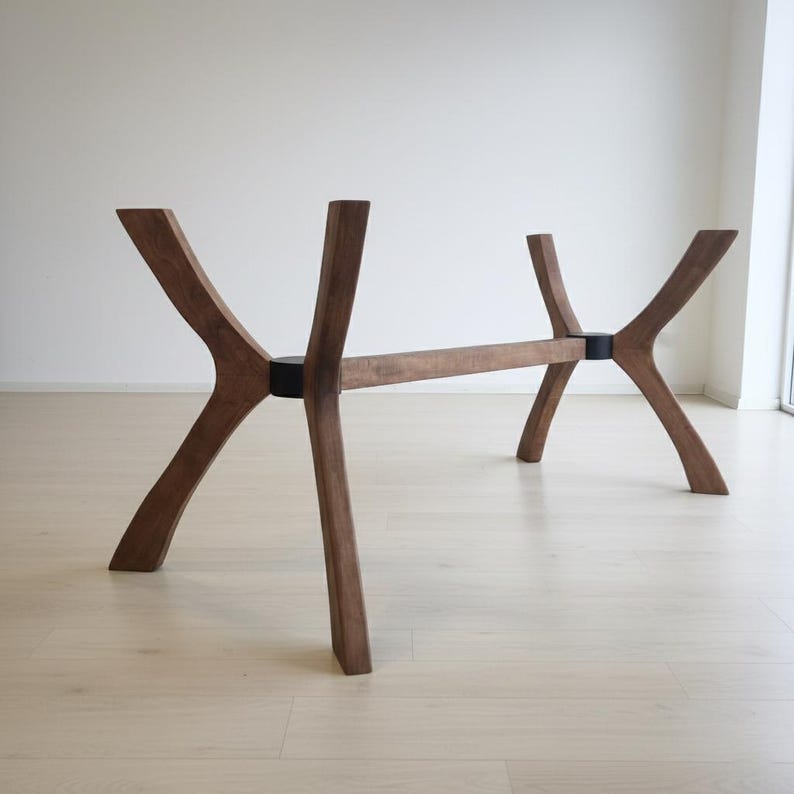 Puede incluir: Una base de mesa de madera con un dise&ntilde;o &uacute;nico y moderno. La base presenta cuatro patas anguladas conectadas por una viga horizontal. Las patas son de color marr&oacute;n oscuro y las uniones de conexi&oacute;n son negras. La base de la mesa est&aacute; dise&ntilde;ada para soportar una tapa de mesa.