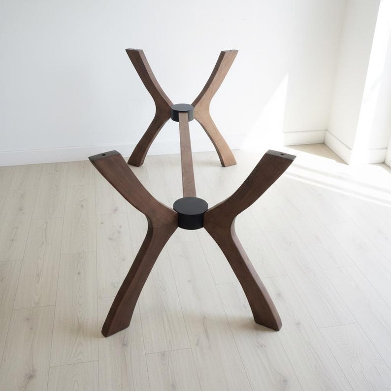 Puede incluir: Dos bases de mesa de madera con acabado marr&oacute;n oscuro. Cada base tiene cuatro patas curvas que se unen en el centro, conectadas por una viga de soporte central. Las patas est&aacute;n unidas con conectores circulares negros. Las bases est&aacute;n dise&ntilde;adas para una est&eacute;tica moderna.