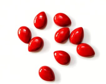May include: Ten red teardrop-shaped cabochons, likely gemstones, on a white background.