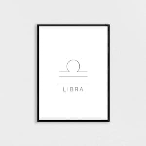 K&ouml;nnte beinhalten: Ein gerahmter Druck mit dem Sternzeichen Waage. Das minimalistische Design zeigt eine Strichzeichnung der Waage und das Wort &bdquo;LIBRA&ldquo; in Schwarz auf wei&szlig;em Hintergrund. Der Rahmen ist schwarz.