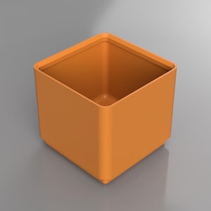 May include: A square, orange container with rounded corners and a smooth finish. The container has a hollow interior and sits on a flat surface. The design is minimalist and modern, suitable for various uses.