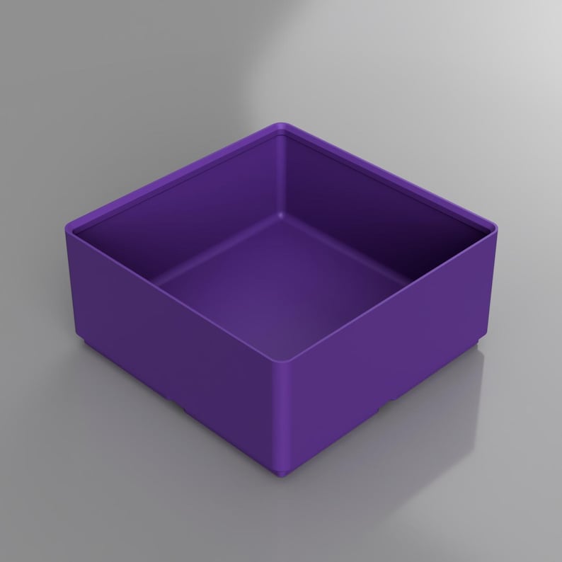 May include: A square, purple storage box with a low profile. The box is a solid color and has a simple, modern design. The interior and exterior are the same shade of purple. The box is sitting on a gray surface.