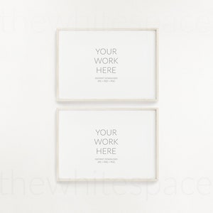 May include: Two white picture frames with a light wood border, hanging on a white wall. The frames are empty and have the text "YOUR WORK HERE" and "INSTANT DOWNLOAD JPG PSD PNG" printed inside.