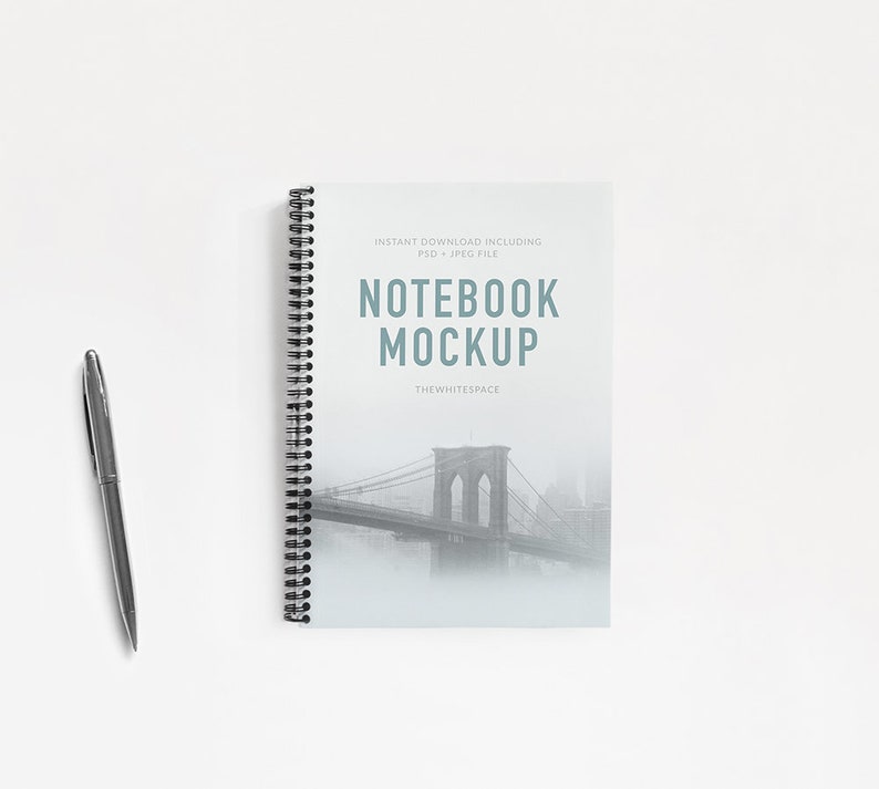 May include: A black and white photo of the Brooklyn Bridge is featured on the cover of a spiral bound notebook mockup. The text "NOTEBOOK MOCKUP" is printed in blue on the cover. The text "INSTANT DOWNLOAD INCLUDING PSD + JPEG FILE" is printed in gray on the cover. The text "THEWHITESPACE" is printed in gray on the cover.
