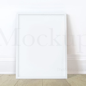 May include: White picture frame mockup on a white wall with a wood floor. The frame is empty and ready for your design.