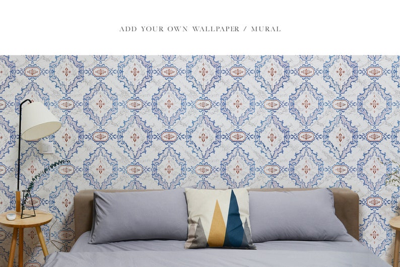 May include: A bedroom with patterned wallpaper featuring a blue and white geometric design. The wallpaper has a subtle red accent. A bed with grey linens and a geometric patterned pillow is in the foreground. A lamp with a white shade is on the left side of the image. A small wooden table with a white object on top is in the foreground.