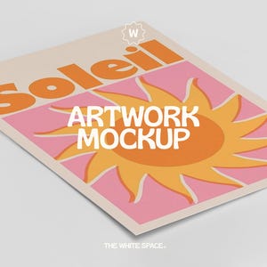 May include: A beige poster with the word "Soleil" in orange letters and a stylized orange sun on a pink background. The text "Artwork Mockup" is in white letters below the sun. The poster has a white "W" sticker in the upper right corner and the text "THE WHITE SPACE." at the bottom.