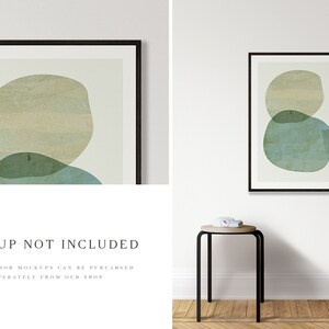 May include: A black framed print featuring an abstract design of overlapping green and beige circles against a white background. The print is hanging on a white wall above a black stool. The text "MOCKUP NOT INCLUDED" is printed below the image.
