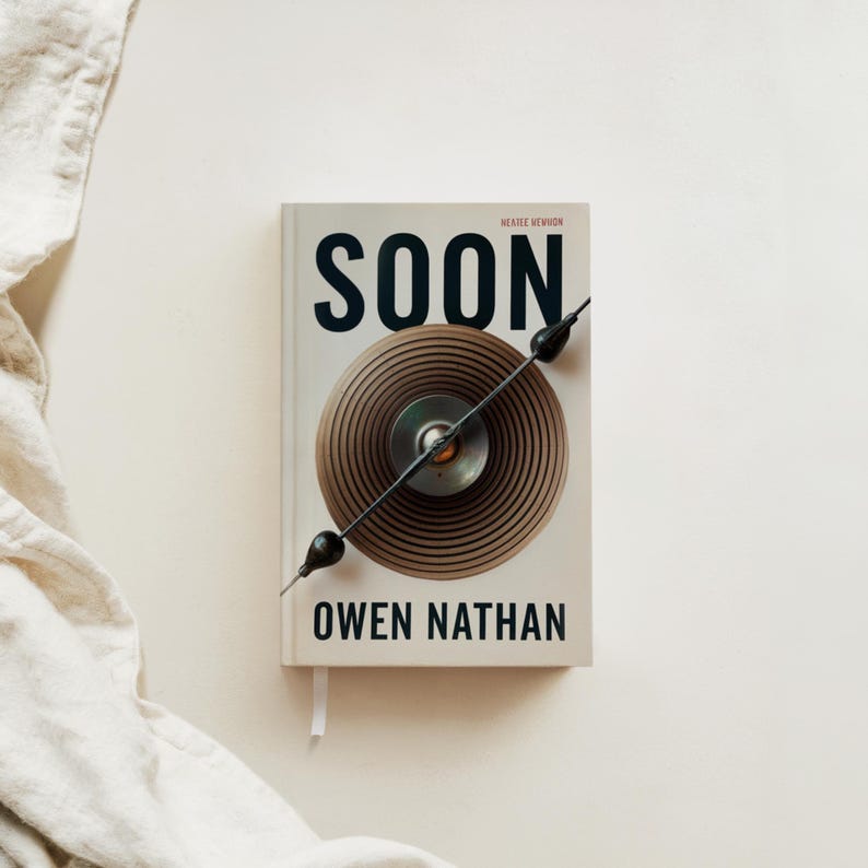 May include: A white book with the title "SOON" in black text. The book has a black and brown circular design on the cover. The author's name, "OWEN NATHAN", is printed in black below the design. The book is titled "SOON" by Owen Nathan.