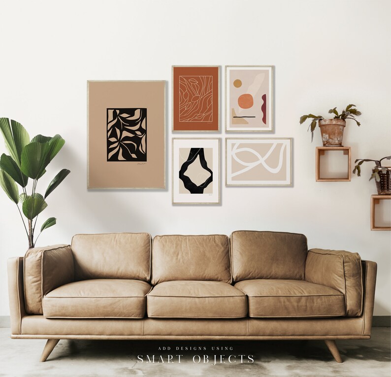 May include: Five abstract art prints in black, white, and orange frames, hanging on a white wall above a brown leather sofa. The prints feature geometric shapes, lines, and organic forms.