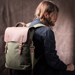 May include: A green canvas and brown leather backpack with adjustable straps and buckles.