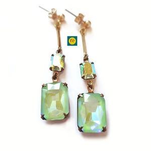 May include: A pair of gold dangle earrings with two green iridescent rectangular stones on each earring.