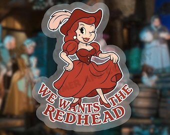 May include: A sticker featuring a cartoon woman in a red dress and hat, winking. The text "We Wants The Redhead" is in a red, outlined font. The background is blurred, suggesting a themed environment.