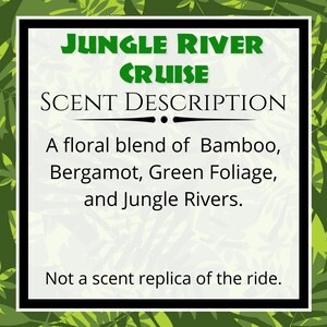 May include: A white sign with a black border and green text that reads "JUNGLE RIVER CRUISE SCENT DESCRIPTION." The text describes a floral blend of bamboo, bergamot, green foliage, and jungle rivers. The bottom of the sign reads "Not a scent replica of the ride."