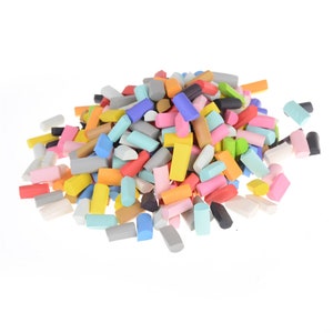May include: A large pile of colorful foam craft sticks in various shapes and sizes. The sticks are arranged in a random pattern and are mostly rectangular, with some being rounded or oval.