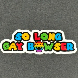 May include: A white sticker with the text "So Long Gay Bowser" in rainbow colors. The text is in a bold, cartoon font. A rainbow Bowser head is in the middle of the text.