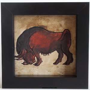 May include: A square black frame containing a relief artwork of a bull in shades of deep red and dark brown. The bull is depicted in a lowered head stance against a textured, light tan background. The text EREDHESETSY.COM is printed at the bottom.