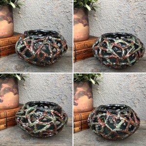 May include: A ceramic bowl with a unique, intricate design. The bowl is made of brown and green clay and has a lattice-like pattern. It is a decorative piece that would be perfect for a home or garden.