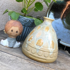 Op de afbeelding: Een keramische vaas met een lichtbruine en witte glazuur. De vaas heeft een afgeronde vorm met een brede opening aan de bovenkant. De vaas is versierd met een patroon van kleine, onregelmatige vormen.